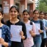 UP Polytechnic Exam 2026 को दर्शाती इमेज जिसमें छात्राएं परीक्षा फॉर्म और एडमिट कार्ड लेकर परीक्षा केंद्र के बाहर लाइन में खड़ी दिखाई दे रही हैं।