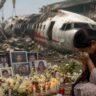 AI 171 Crash Investigation Report से जुड़ी भावुक तस्वीर, जिसमें विमान हादसे में जान गंवाने वाले लोगों की याद में शोक व्यक्त करती एक महिला और श्रद्धांजलि स्थल दिखाई दे रहा है।