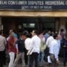 Delayed Flat Possession Refund मामले से जुड़ी तस्वीर, जिसमें उपभोक्ता आयोग के बाहर फ्लैट खरीदार और कानूनी प्रक्रिया से जुड़े लोग दिखाई दे रहे हैं।