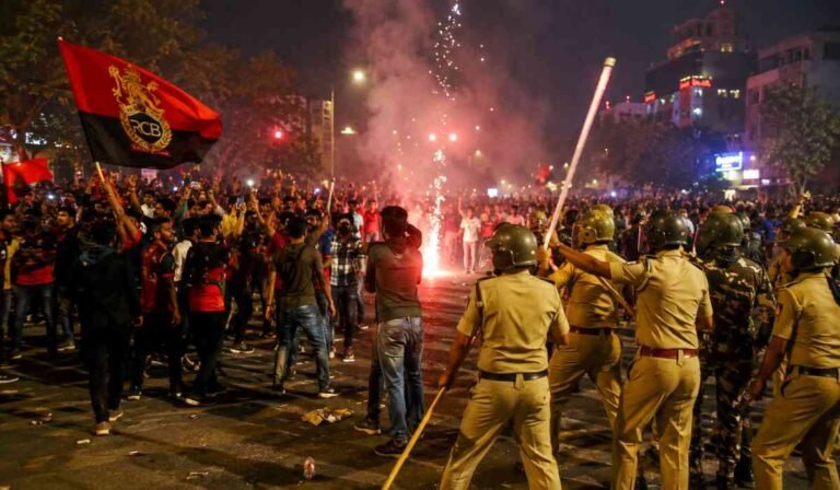 RCB IPL 2026 जीत के बाद सड़क पर जश्न मनाते और पुलिस द्वारा नियंत्रित किए जाते क्रिकेट फैंस का दृश्य।