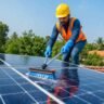 Solar Panel Cleaning Tips के तहत छत पर लगे सोलर पैनल को सुरक्षित तरीके से साफ करता हुआ तकनीशियन।